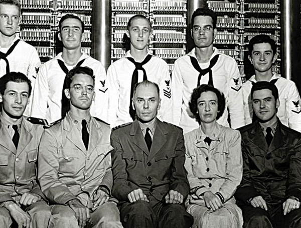 Grace Hopper (seated second from right), with other members of the Bureau of Ordnance Computation Project, in front of the Harvard Mark I computer. Photo courtesy of Defense Visual Information Center