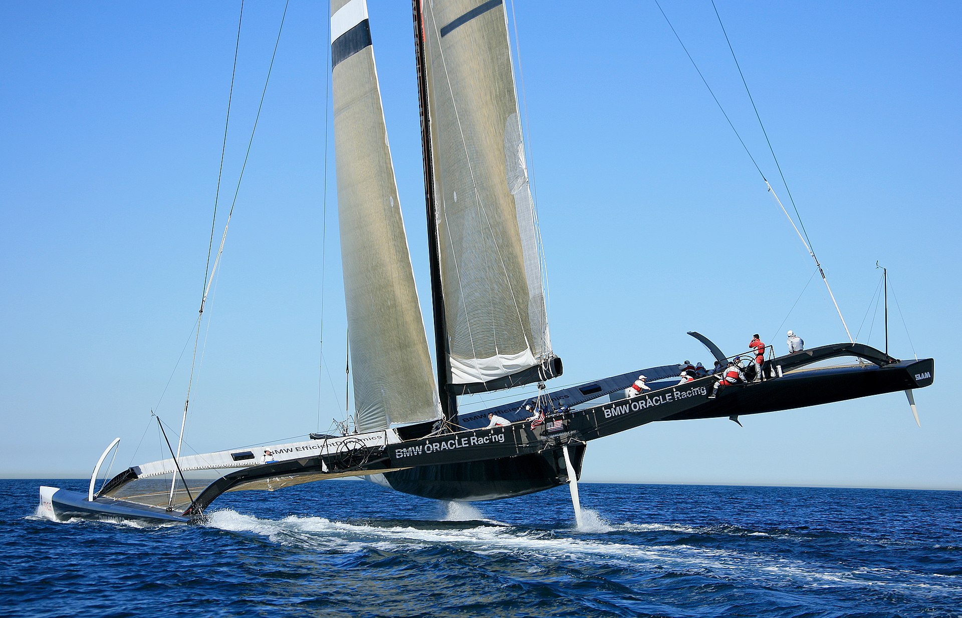 Crewmen look like dwarfs on the massive trimaran. Its original design, shown here in trials off San Diego, included a conventional sail. Photo by Limeydal.